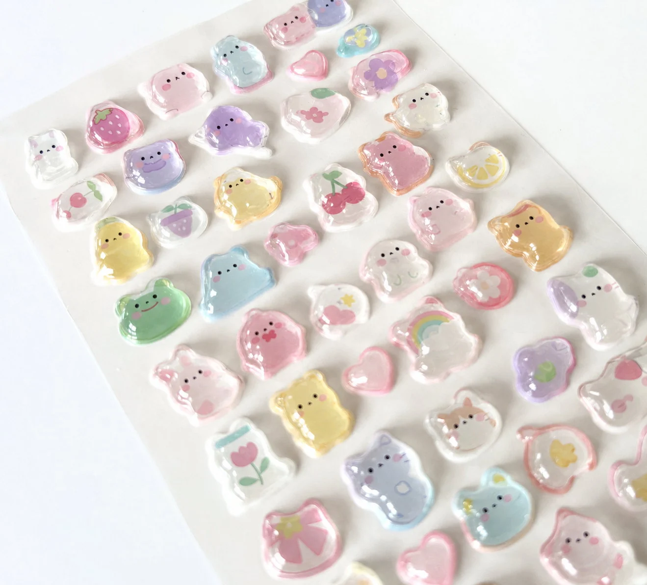 Stickers brillants et bombés illustrés de petits animaux, de fleurs et de fruits, sur une planche échantillon